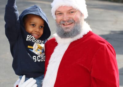 volunteer dressed as santa holds young boy